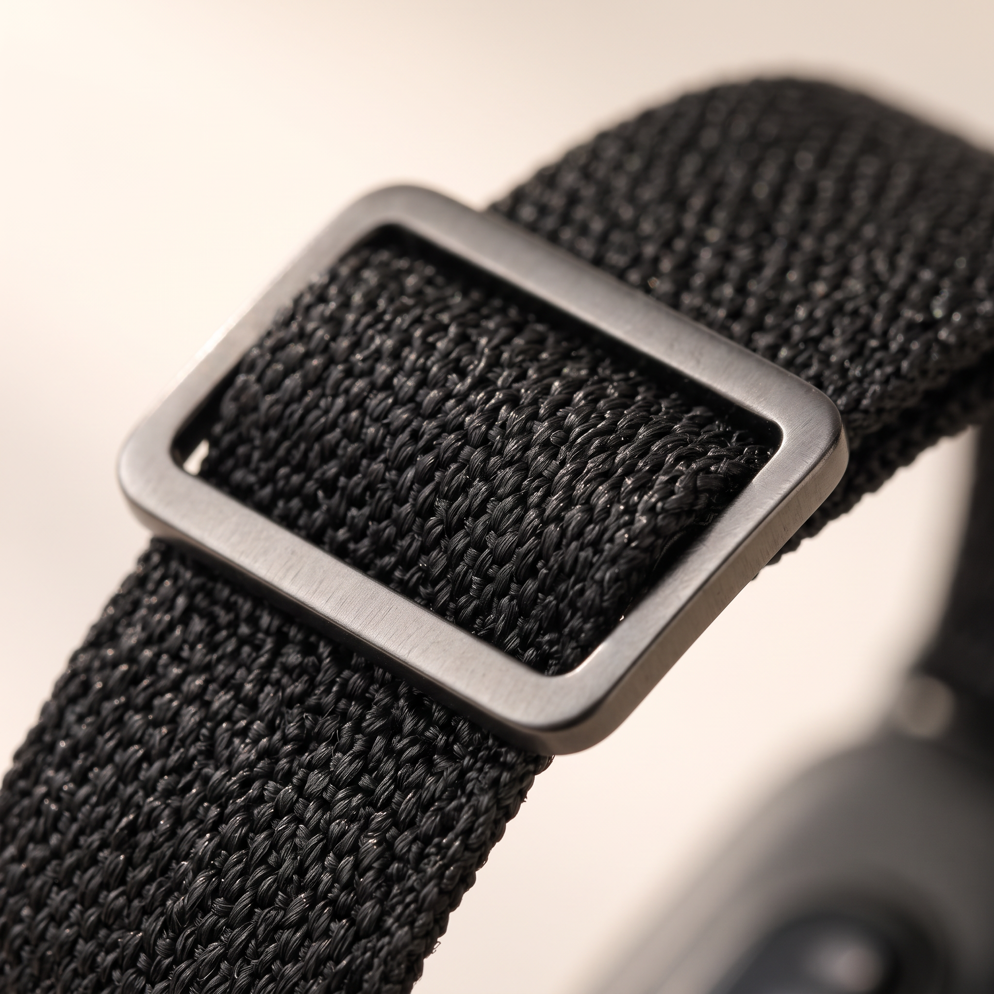 Close-up of the brushed metal slide buckle on the woven strap